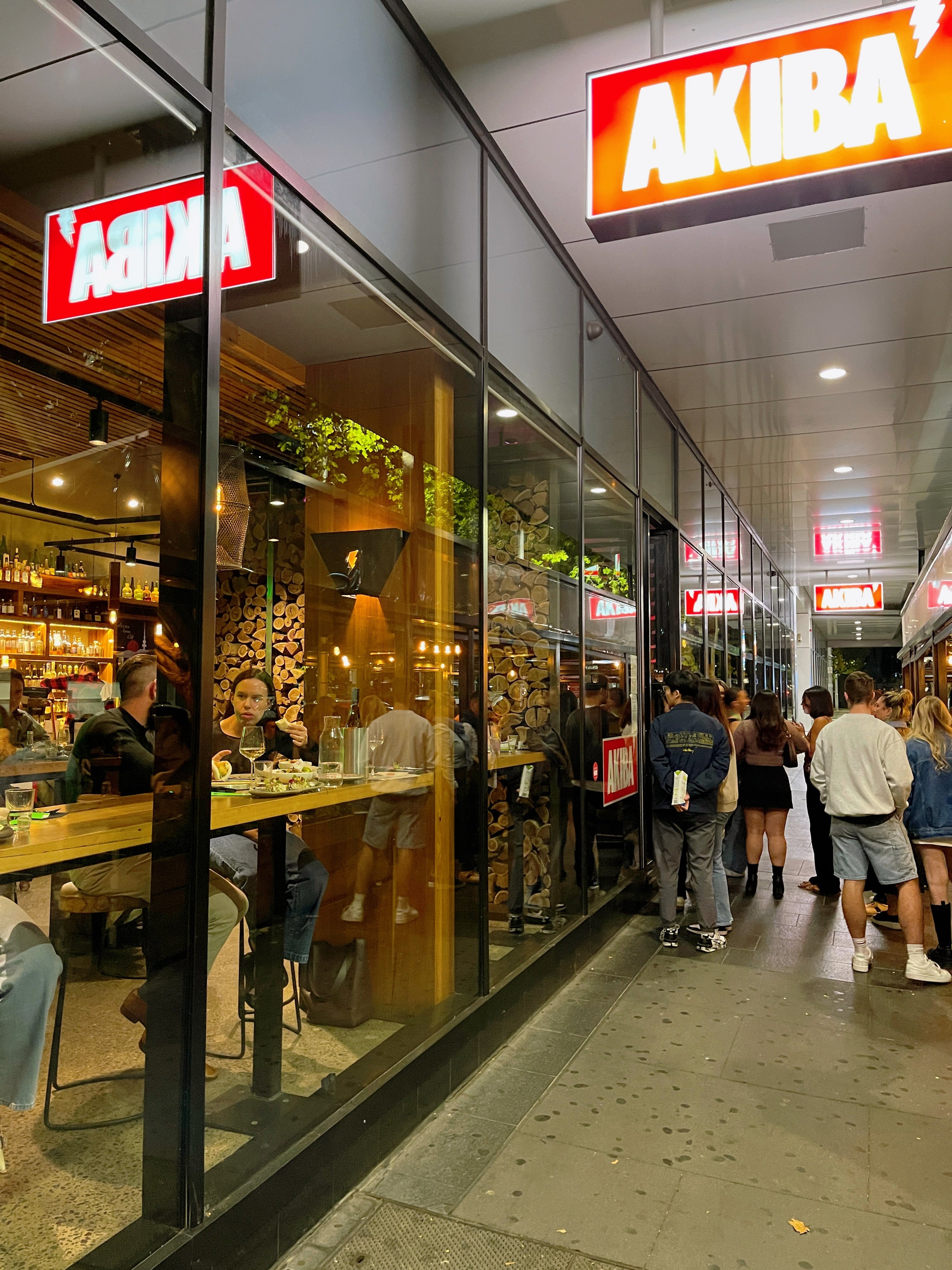 Outside a busy restaurant in Canberra, many people are lining up to get in to have dinner.