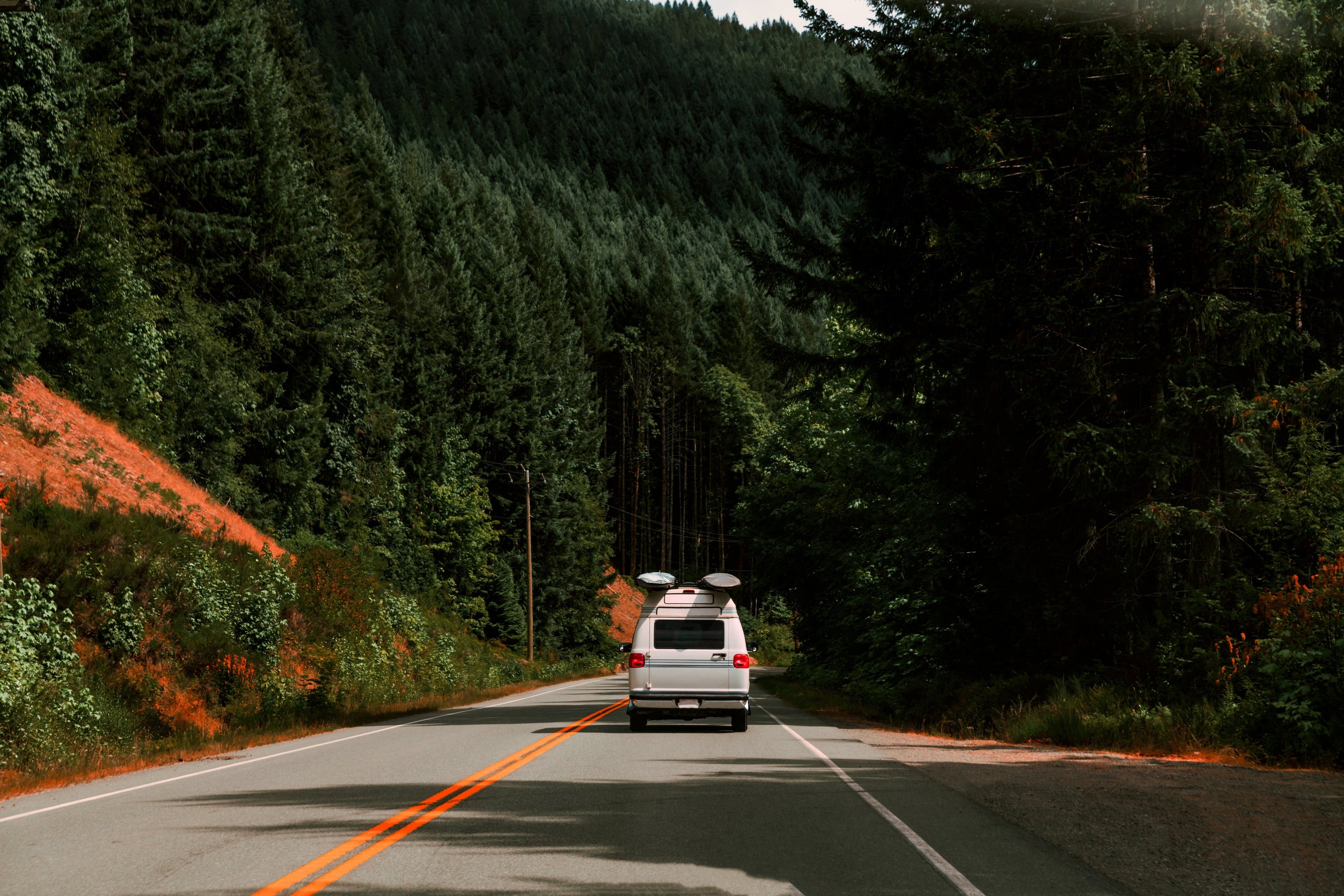Adventure is just around the corner as this Van drives through the lush green mountain scenery.