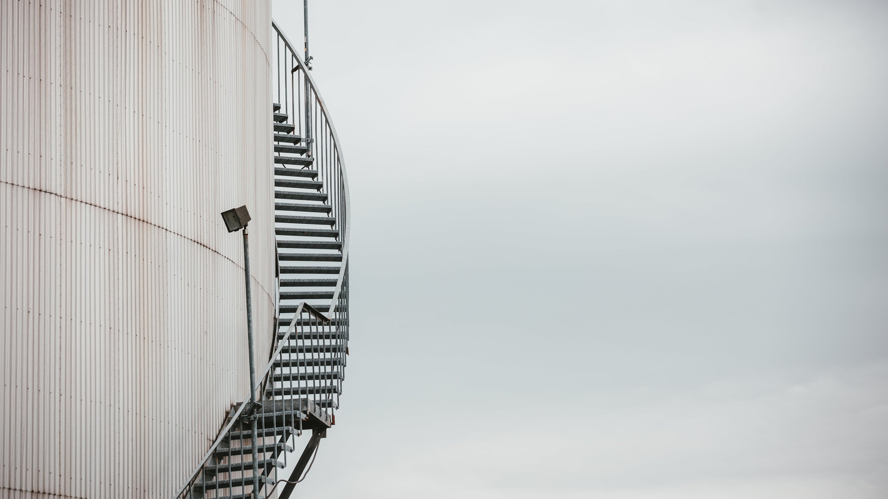 An iron staircase winds round the exterior of a corrugated iron building - is it a water tower?