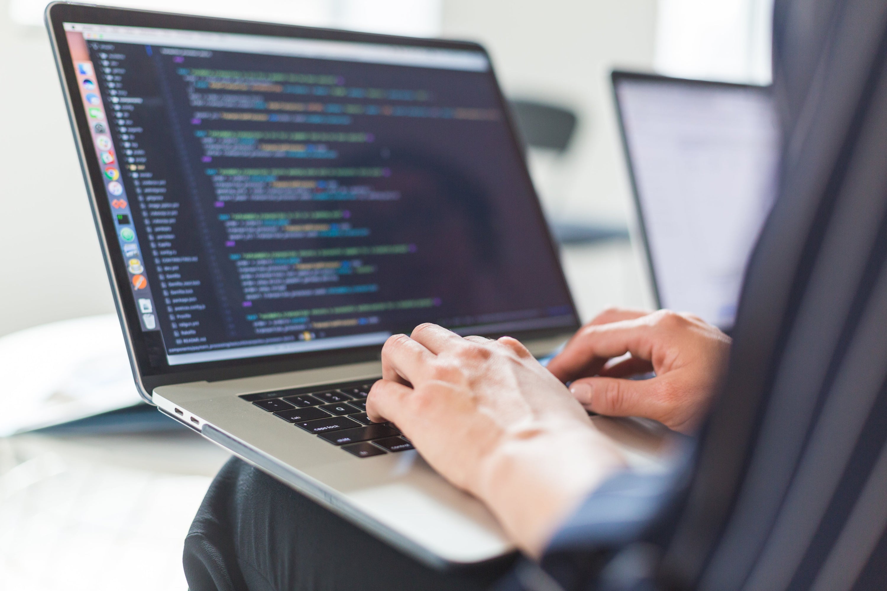 Coding on a laptop. A person typing code and working on development for their business