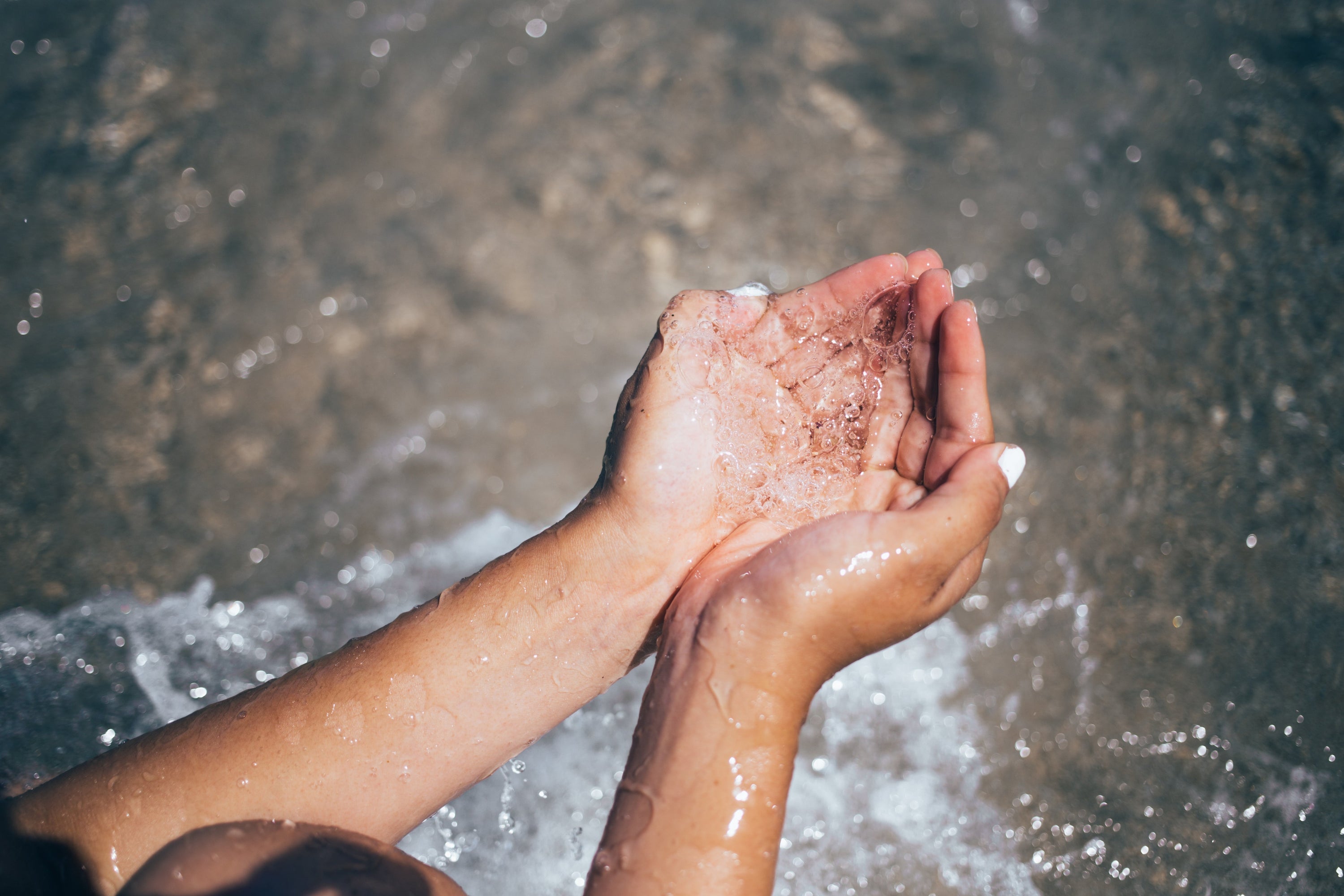 Clear water falls through a pair of beach goers hands