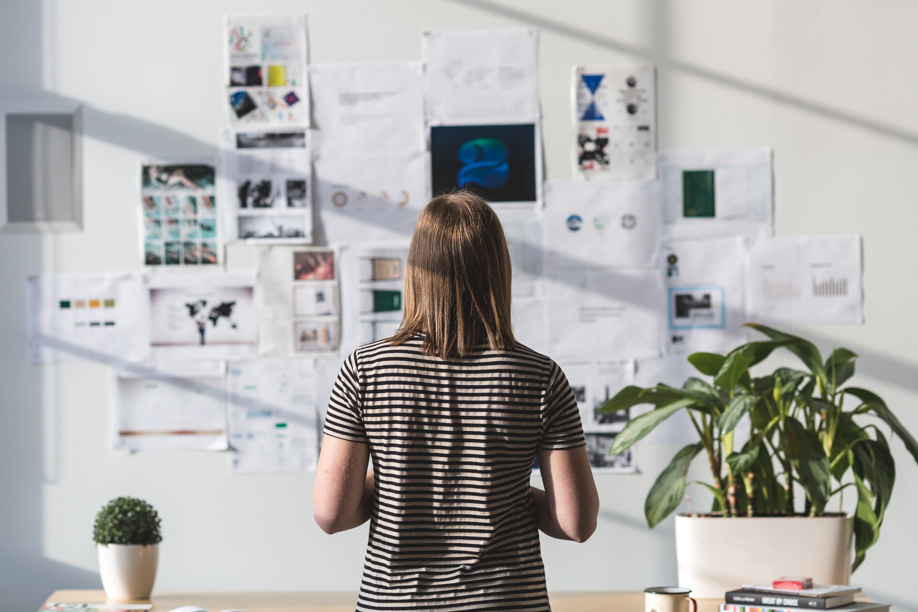 A woman stands in front of a wall of coffee analytica's office. Getting creative ideas can come from many places and this workspace is clearly full of brainstorms, inspirational walls and ideas ready to come to life in AGI era.