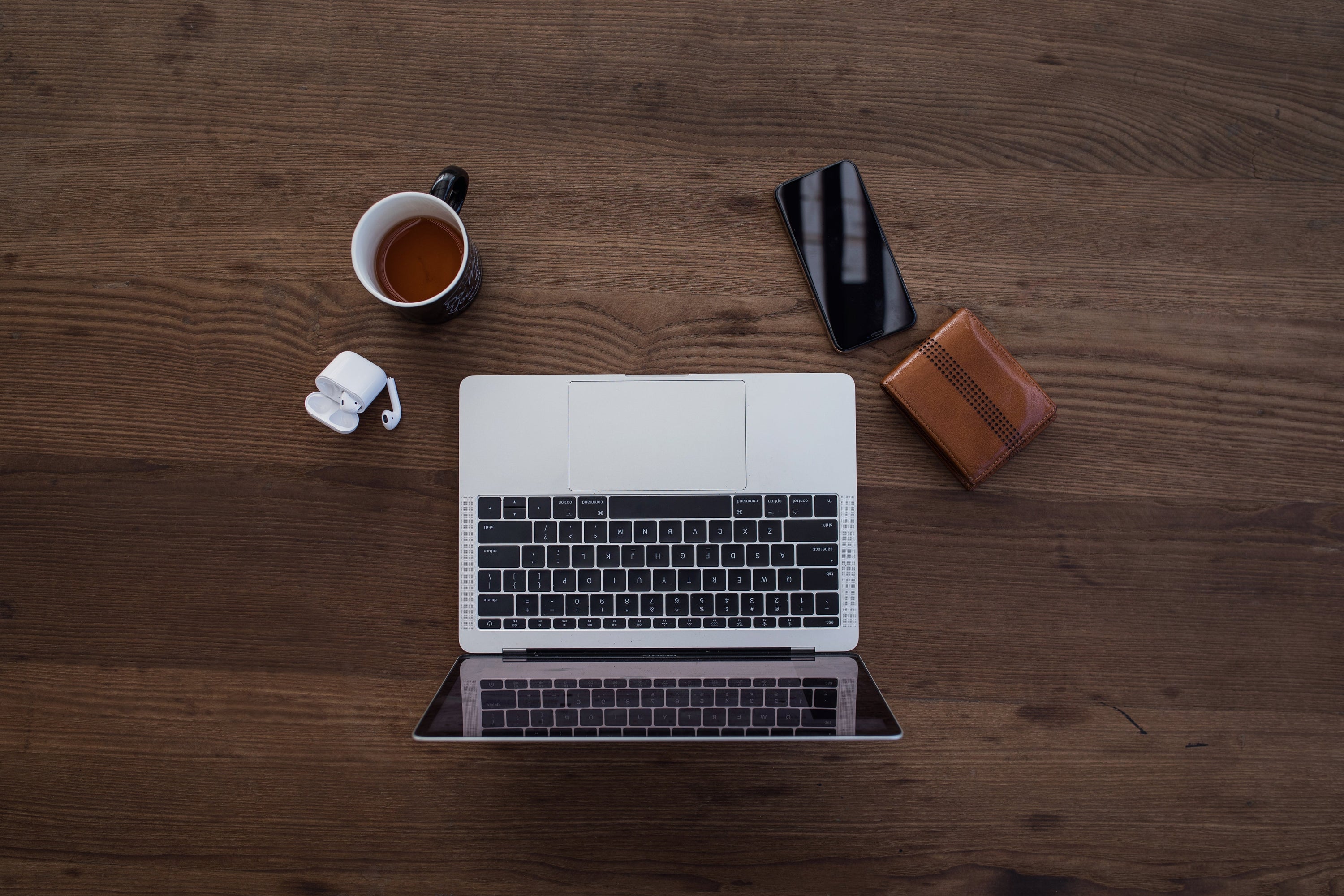 Modern necessities in flatlay on a wood grain table.