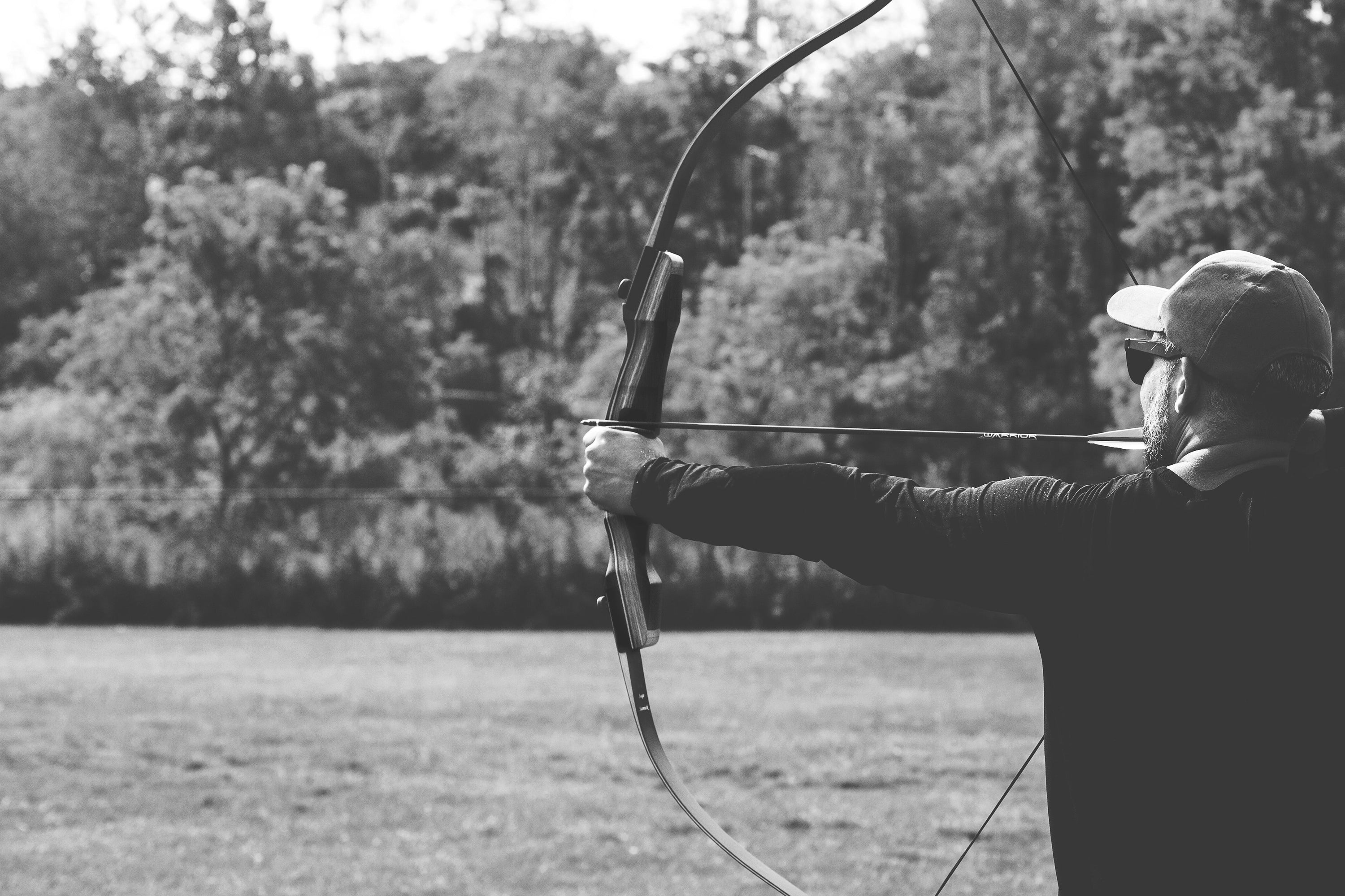 An archer takes aim with his bow and arrow in black and white. Ready, aim ...