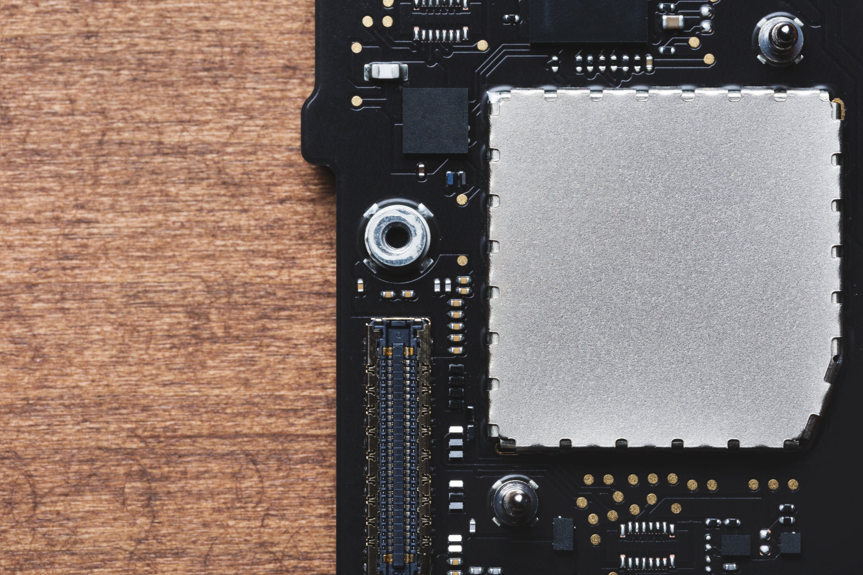 A close-up shot of a motherboard. There is a wood texture to the left.