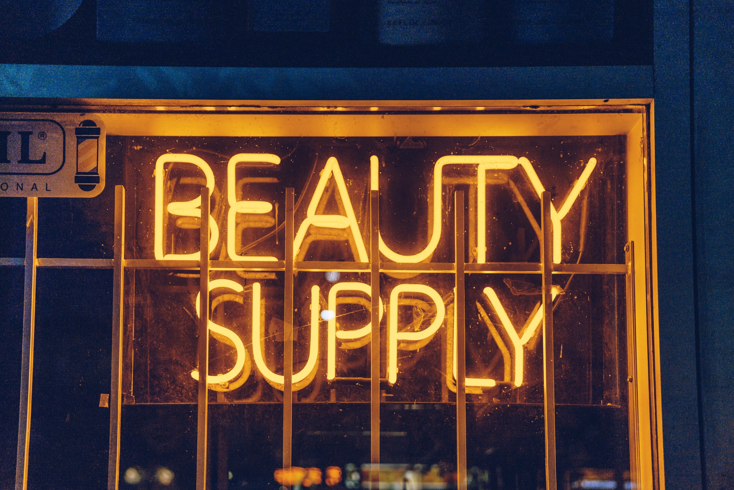 Yellow beauty supply shop sigh glows in the night. The shop may not be open but the sign runs all night to let customers know it is there.