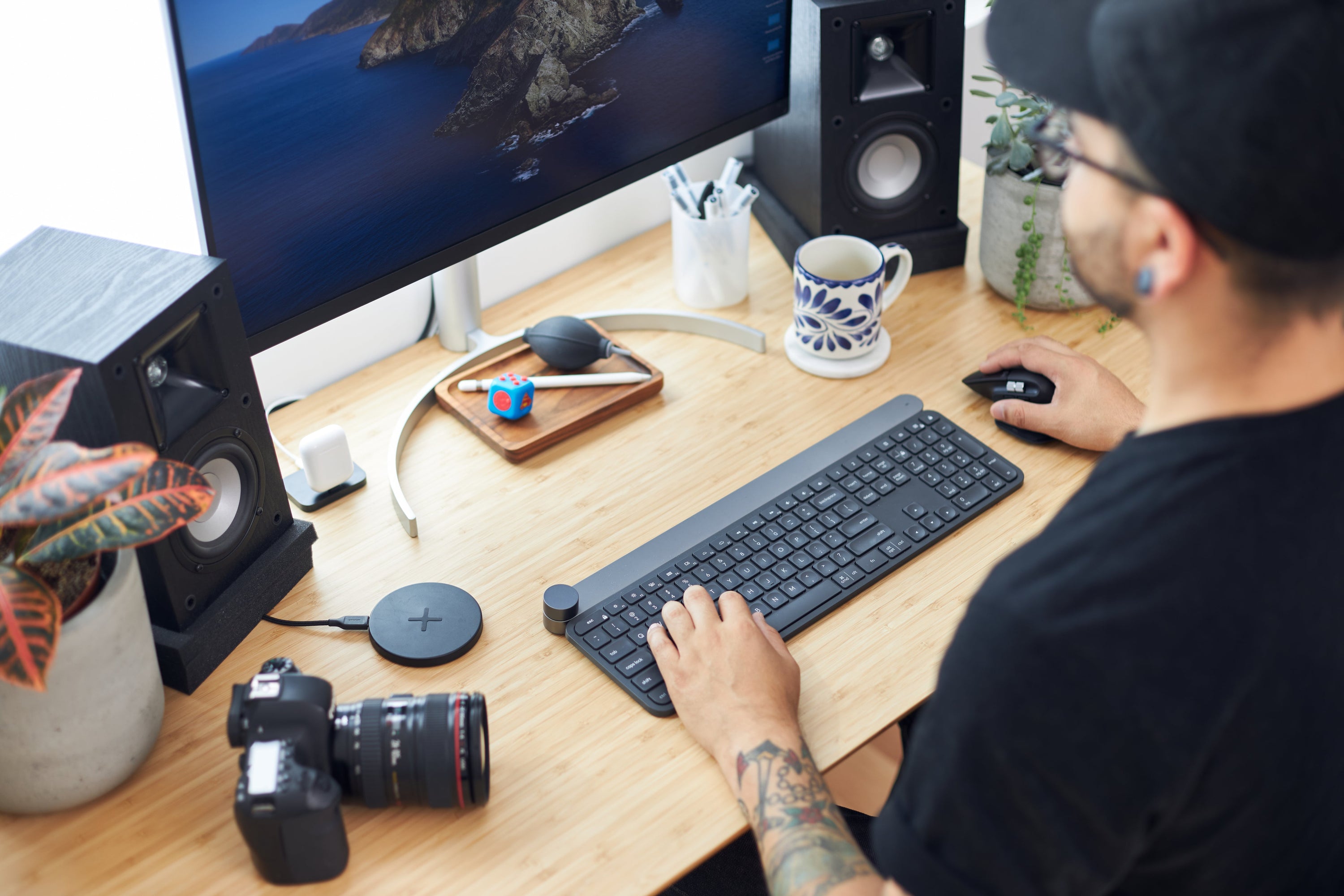 A photographer sits in front of his computer in a brightly lit working space.