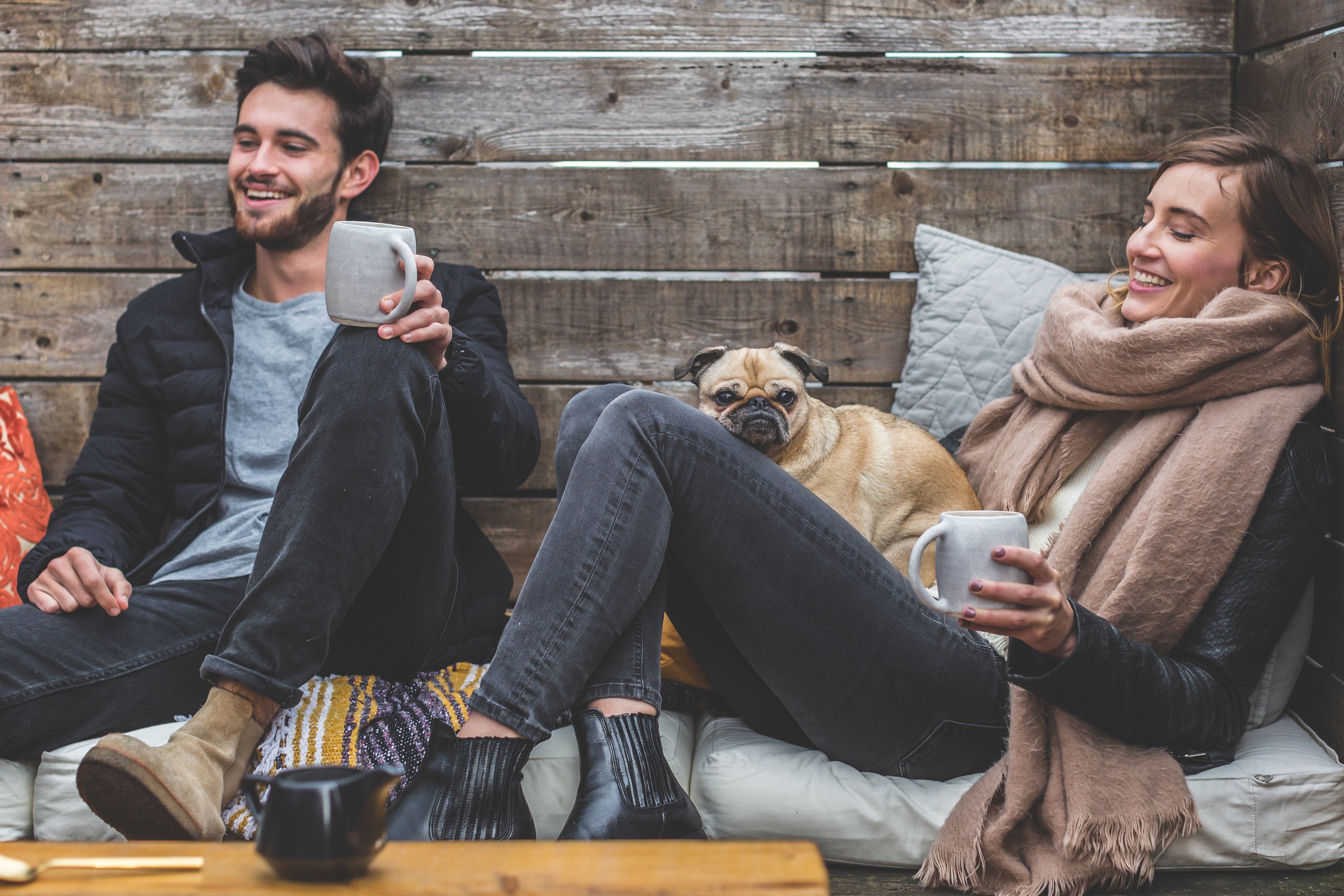 Man and woman Relax outside with pug dog and coffee.