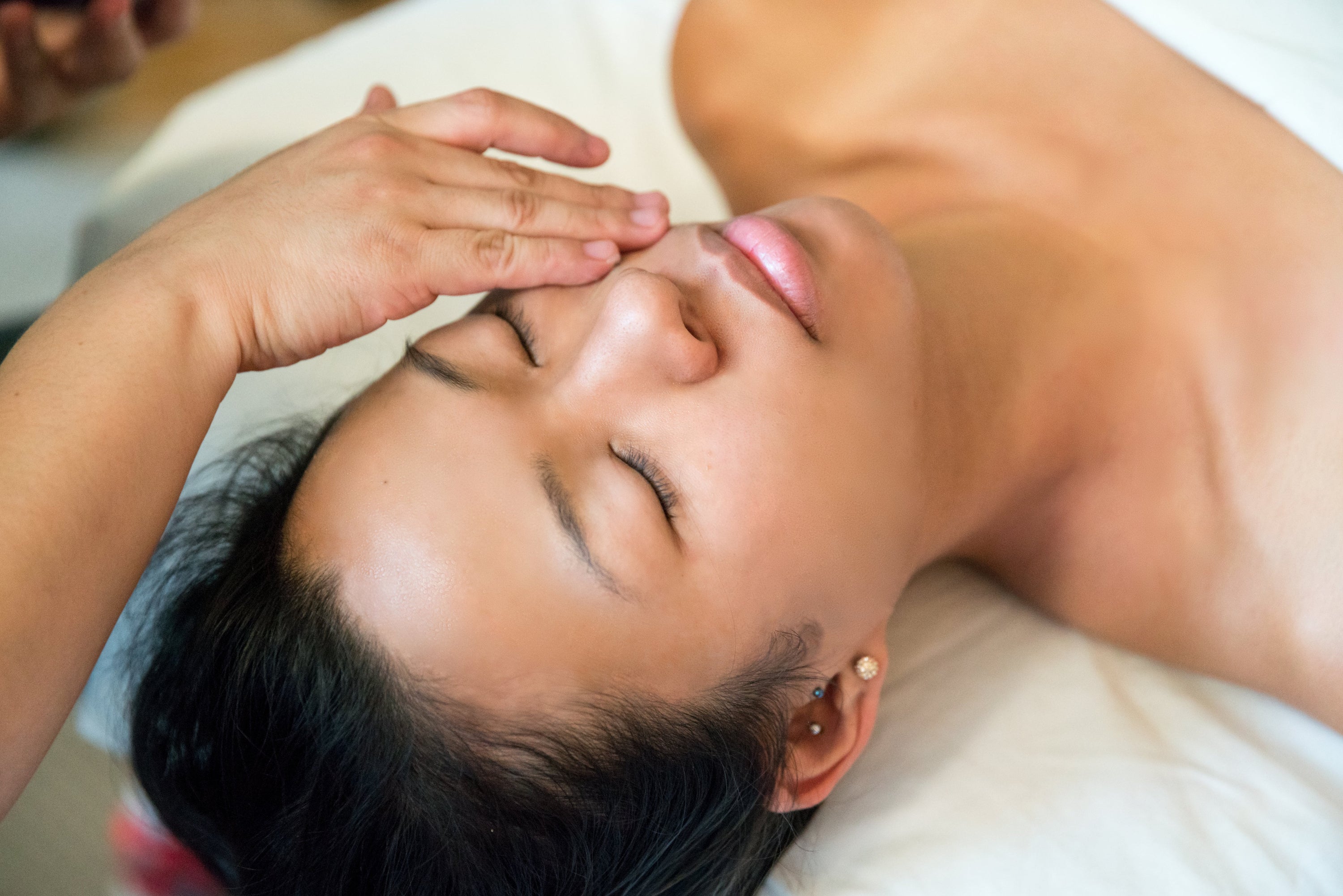 A woman closes her eyes as somebody else gives her a facial treatment at the spa.