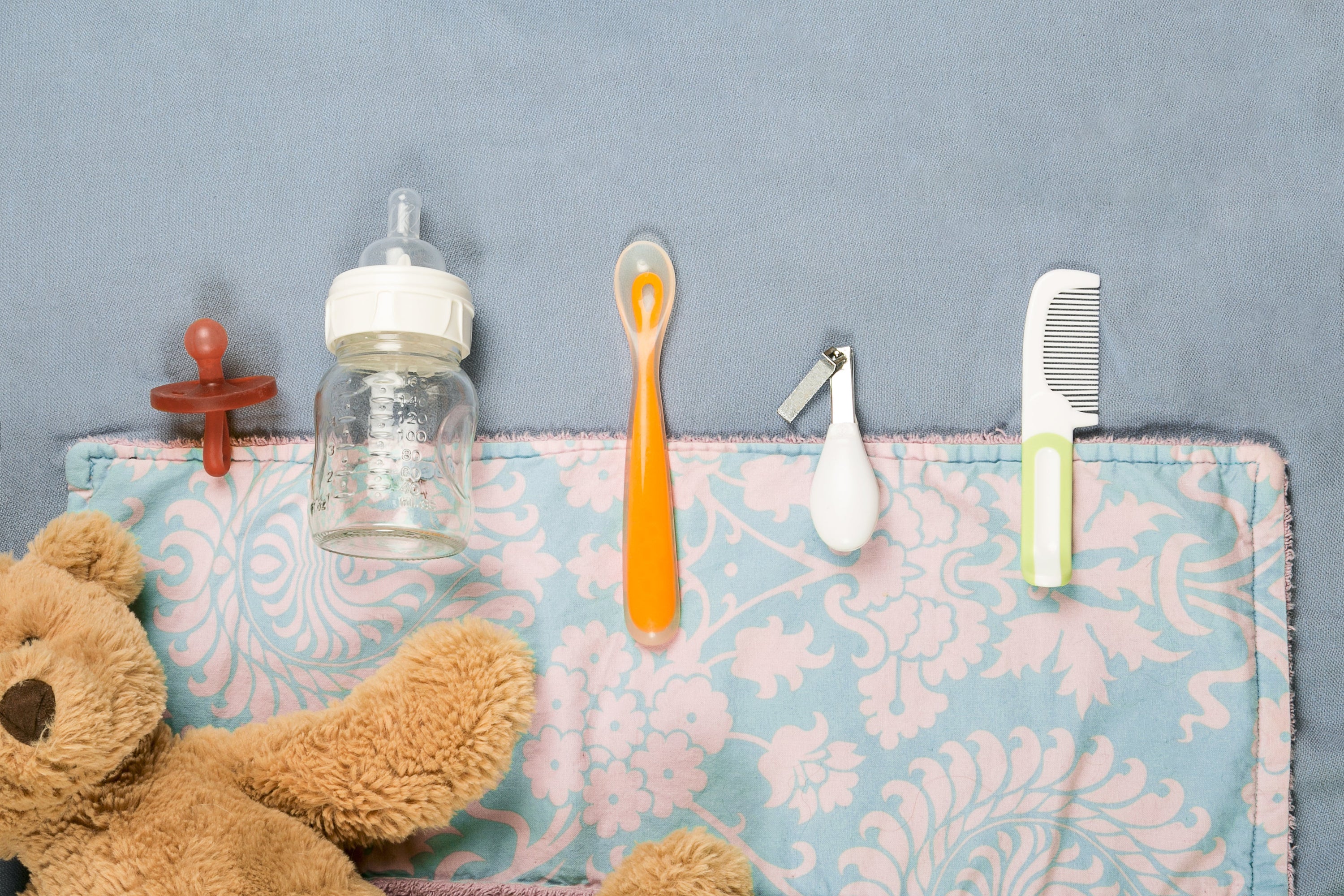 Baby Products lined up on coloured blankets with a toy stuffed bear. 