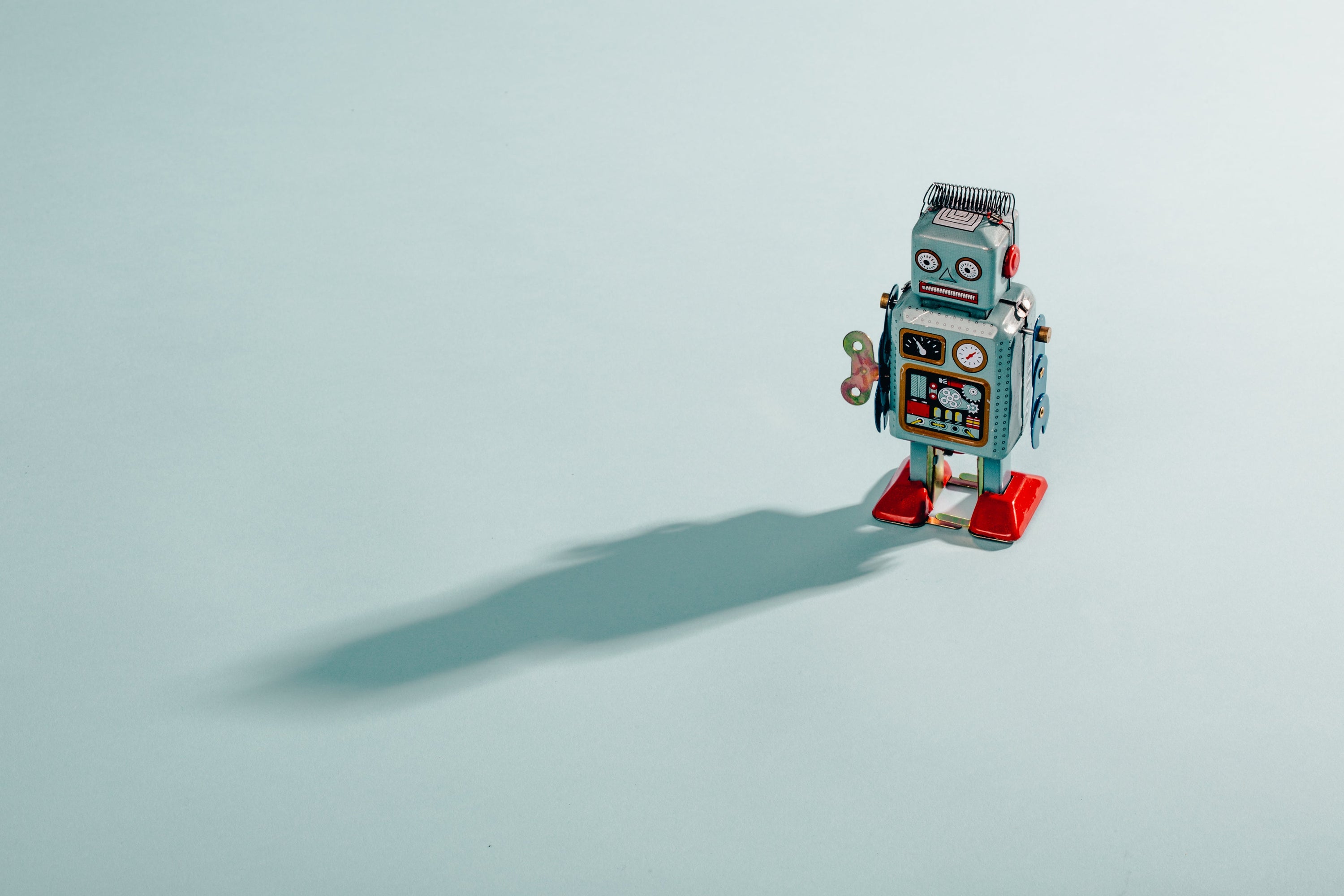 Ominous vintage toy robot casts its shadow over a blue backdrop.