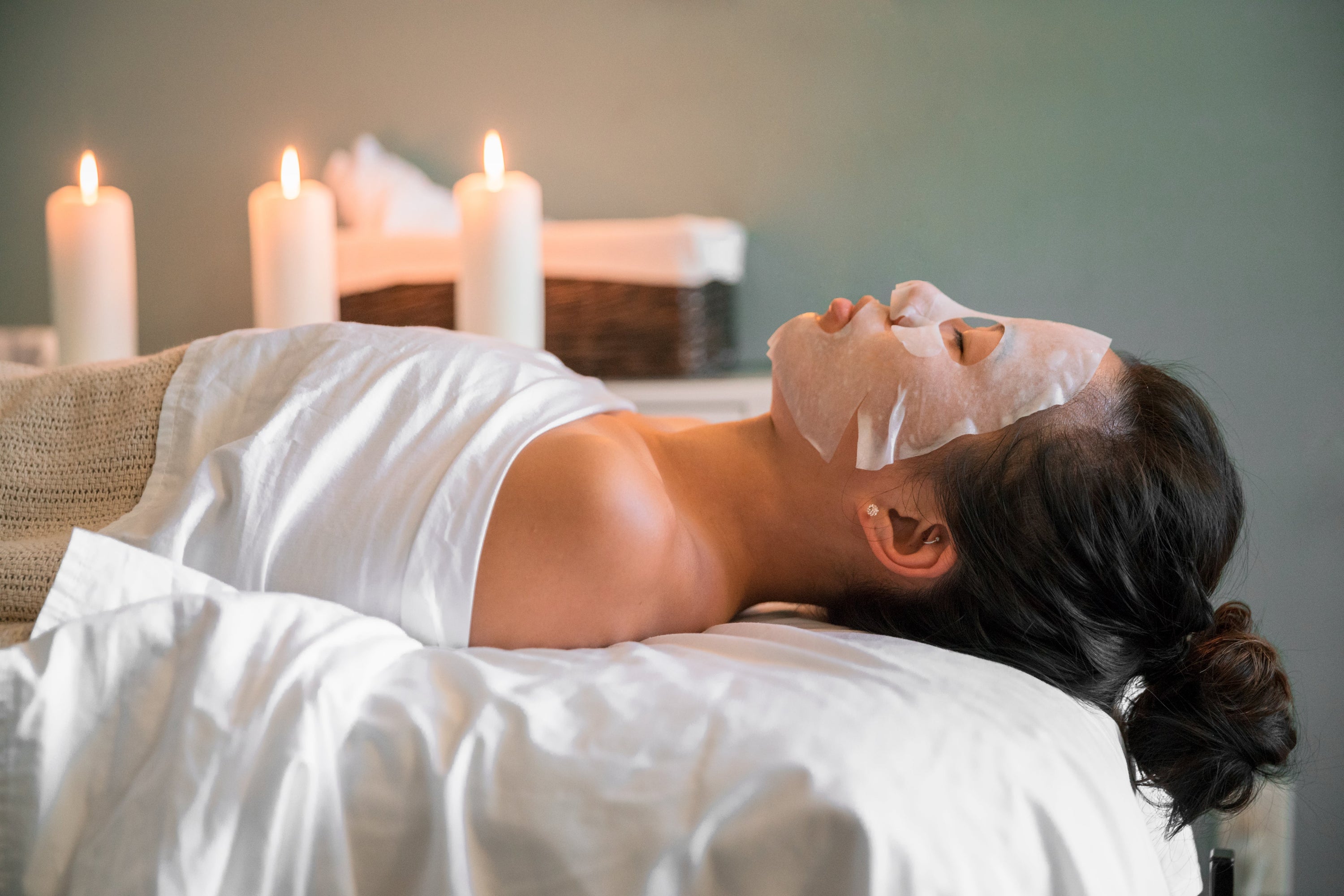 Face mask on, candles lit, ponytail hanging over the edge of a bed -- yes, this woman is ready to relax at a spa.